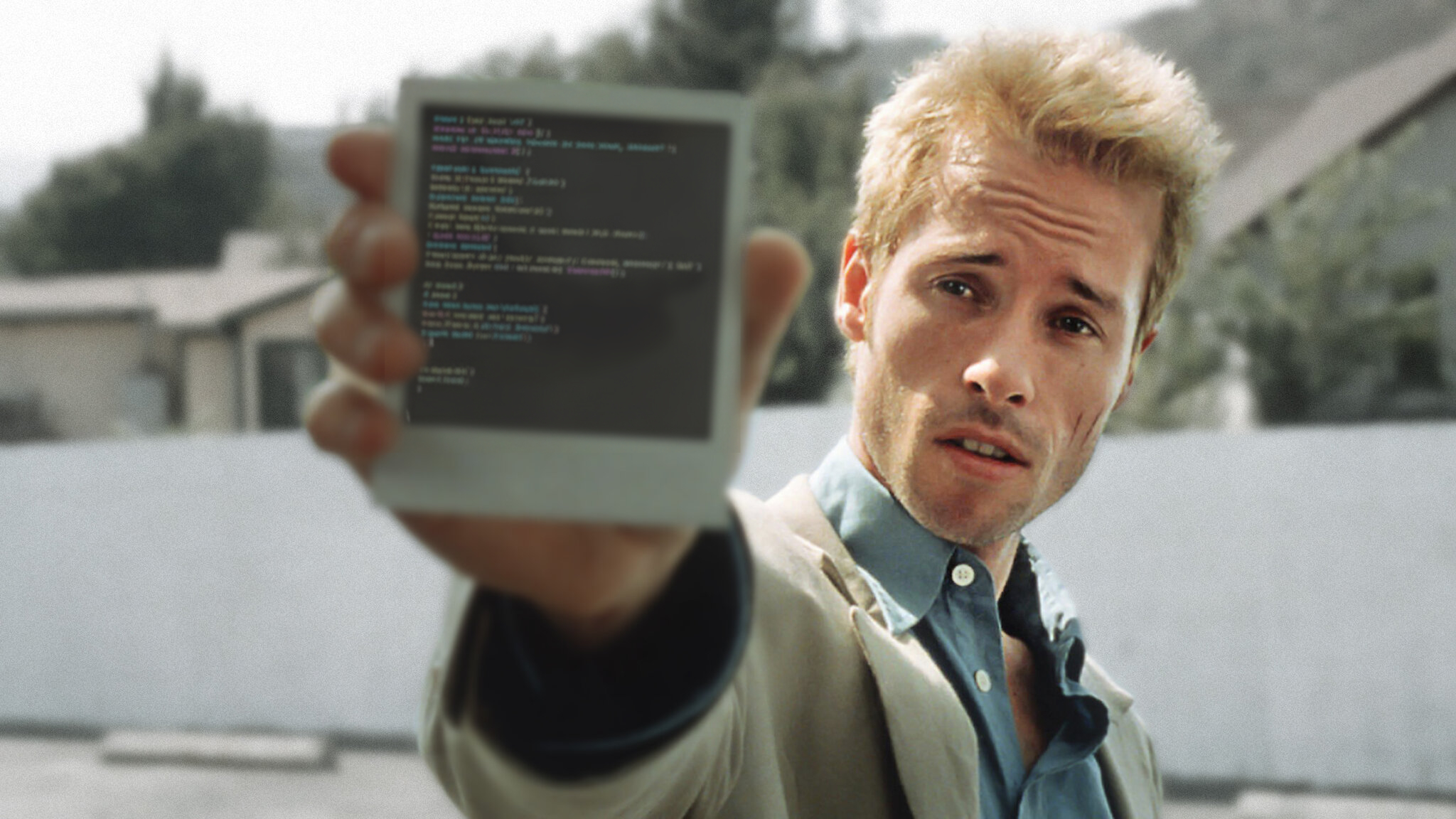 A man holds up a polaroid with some poorly photoshopped code on it